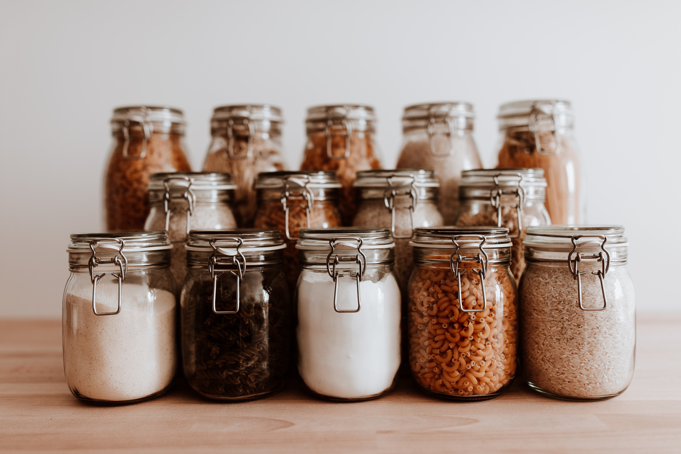Glass jars full with dried uncooked food ingredients.